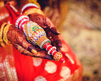 Indian bride with her sindur pot in her hand along with traditional mehendi design in red saree with natural background